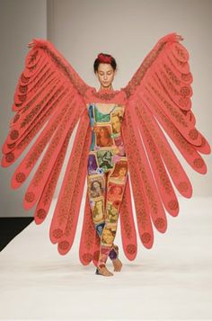 a woman is walking down the runway with an elaborately designed wings on her body