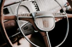 the steering wheel and dashboard of an old car with wood grained dash boards,