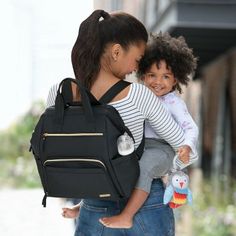 a woman carrying a child in a black backpack on the street with her back to the camera