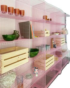 a pink shelf filled with lots of wooden crates