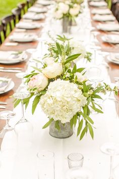 a long table with white flowers and greenery