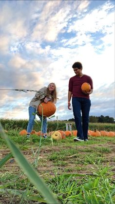 two people in a field with pumpkins