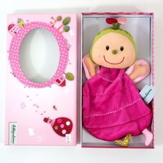 a stuffed doll in a pink box next to a mirror and magnet board with the letter o on it