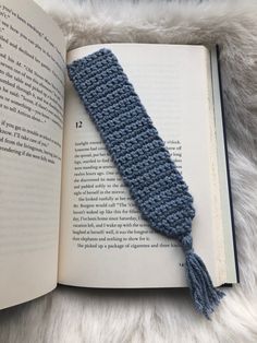 an open book with a crocheted tie on it