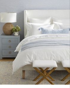 a bed with white linens and blue pillows in a room that is for sale