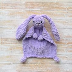 a purple knitted bunny sitting on top of a wooden floor