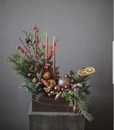 a christmas arrangement with candles, pine cones and other holiday decorations in a wooden container