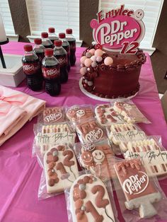 a table topped with lots of cakes and cupcakes next to bottles of soda