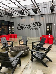 chairs and fire pit in front of the queen city brewing co logo on an industrial building