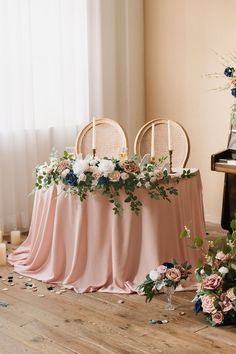 the table is covered with pink cloths and white flowers, along with two chairs