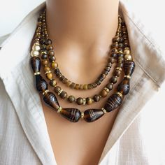 This exquisite piece perfectly combines vibrant Indian glass beads with the earthy allure of Tiger Eye natural stones. Each bead is meticulously handcrafted, showcasing the rich cultural heritage of India. The warm hues of the Tiger Eye stones create a captivating contrast against the intricately designed glass beads, making this necklace a true statement piece. With its adjustable length and secure clasp, it can be easily customized to fit any neckline. Whether you're heading to a special event Cultural Heritage Of India, Beads Making, Brown Gemstone, Mineral Stone, Tiger Eye Stone, Unique Necklace, Glass Bead Necklace, Jewelry Unique, The Tiger