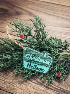 a christmas ornament hanging from a tree on a wooden table with red berries