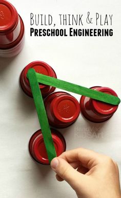 a hand holding a piece of green paper over some red plastic jars with the words build, think and play preschool engineering