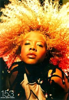 a woman with an afro is looking at the camera and has her hair blowing in the wind