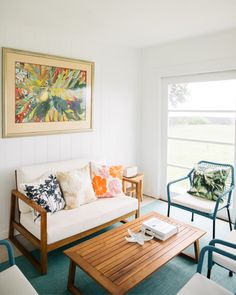 a living room filled with furniture and a painting on the wall above it's windows