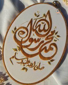 an embroidered design with the words in arabic and gold on a white fabric covered table cloth