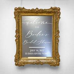 a wedding sign hanging on the wall in front of a white wall with gold frame