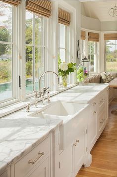 a large kitchen with white cabinets and marble counter tops