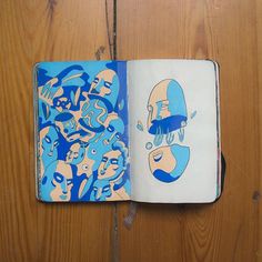 an open notebook with blue and white designs on it, sitting on a wooden surface