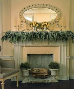 a living room filled with furniture and a fire place covered in greenery next to a mirror