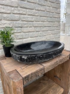 a black bowl sitting on top of a wooden table next to a potted plant