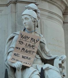 a statue holding a sign that says why pay to live on planet