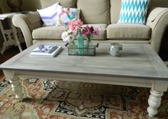 a coffee table with flowers on it in front of a couch