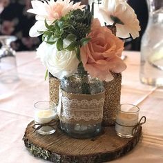 a vase filled with flowers sitting on top of a wooden slice next to two candles