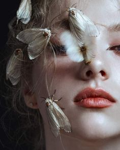 a woman with white butterflies on her face and hair in front of her eyes,