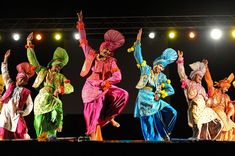 colorfully dressed dancers perform on stage at an event