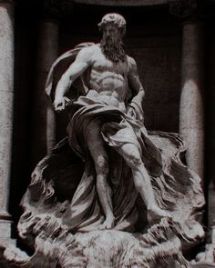 a statue of a man sitting on top of a stone pillar with his hands in his pockets