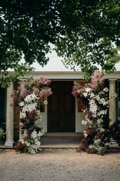 an outdoor wedding venue with flowers and greenery on the front door, surrounded by trees