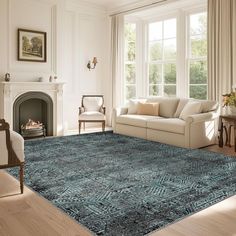 a living room filled with furniture and a blue rug on top of a hard wood floor