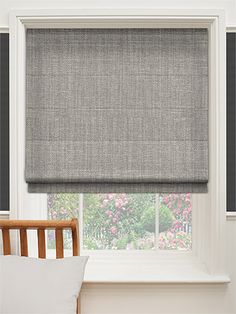 a bedroom with a window covered in gray roman shades