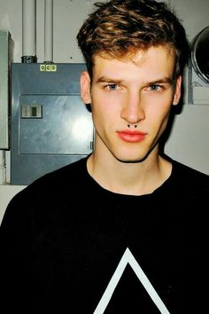 a young man wearing a black shirt with a white triangle on it's chest