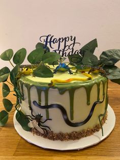 a birthday cake sitting on top of a wooden table next to a green leafy plant