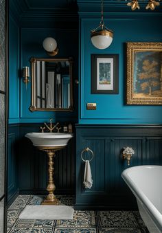 a bathroom with blue walls, gold fixtures and a white sink in the middle of the room