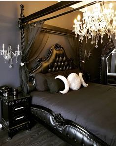 a black bed with an ornate headboard and chandelier