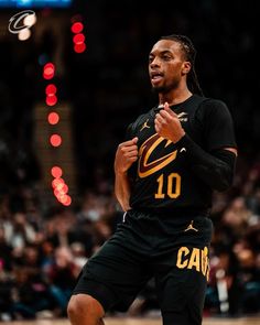 a basketball player in black and gold uniform on the court with his hand up to his chest