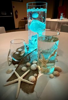 two glass vases sitting on top of a table next to rocks and starfish