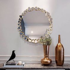 a mirror and vase on a table with a bird figurine next to it