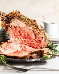 a piece of roast beef on a plate with herbs