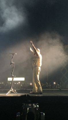 a man standing on top of a stage next to a metal object in the air