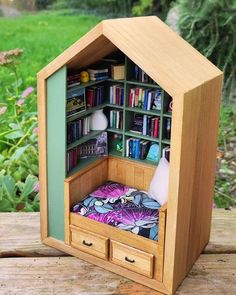 a small wooden bookcase with drawers and books on it's sides, sitting on a table outside