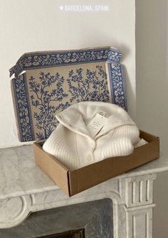 an open box sitting on top of a fireplace next to a white fire place cover