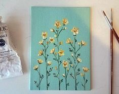 a painting with gold flowers on it next to some paintbrushes and an artist's palette