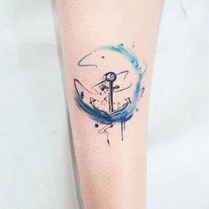 an anchor tattoo on the leg of a person with blue ink splatters around it