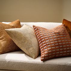 three pillows are sitting on a white couch