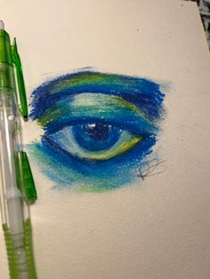 an eye drawn with colored pencils on top of a piece of paper next to a green marker