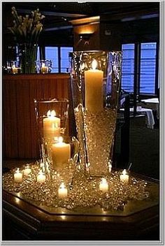 lighted candles are arranged in a tall glass vase